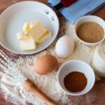 A variety of baking ingredients and eggs out on the table.