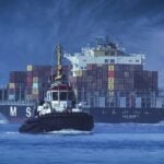 Tugboat in front of a big container ship.