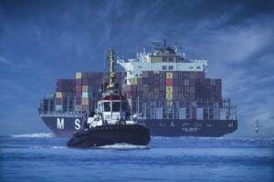 Tugboat in front of a big container ship.