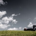 Man lying on the grass, daydreaming and thinking under open sky.