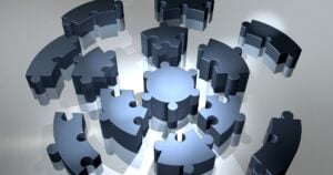 The loose pieces of a metallic, circular puzzle, radiating outwards.