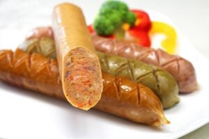 Roasted sausages artfully presented on a plate, with one cut open.