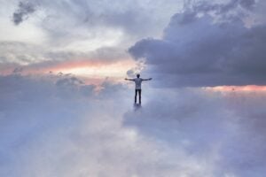 Man high on a peak or cliff balancing among the clouds.