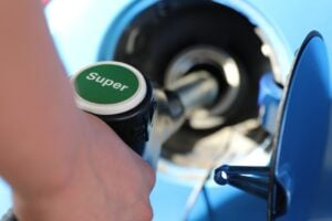 A hand pumping super unleaded fuel into a car.