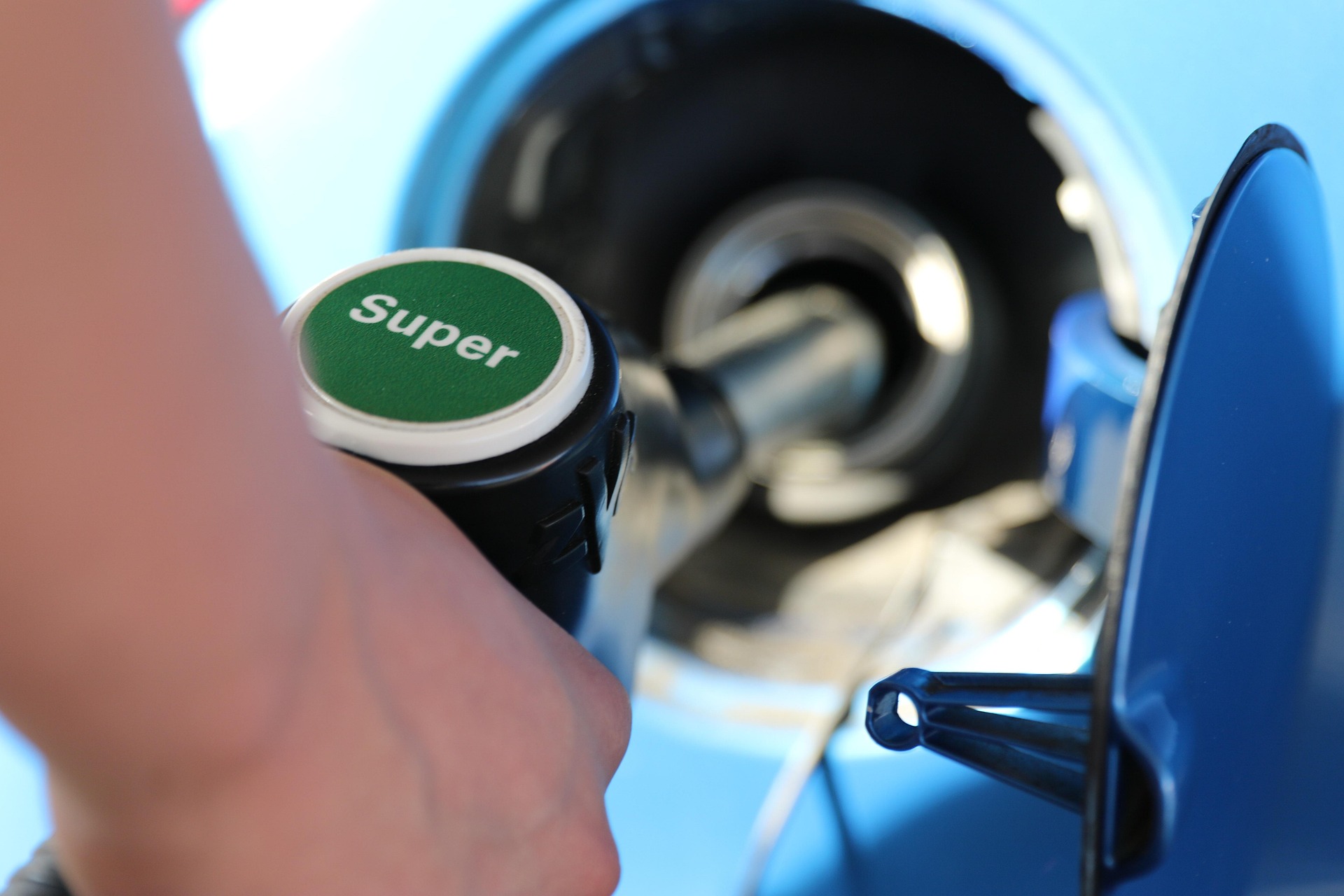 A hand pumping super unleaded fuel into a car.