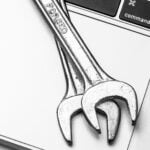 Two wrenches on top of a laptop keyboard.