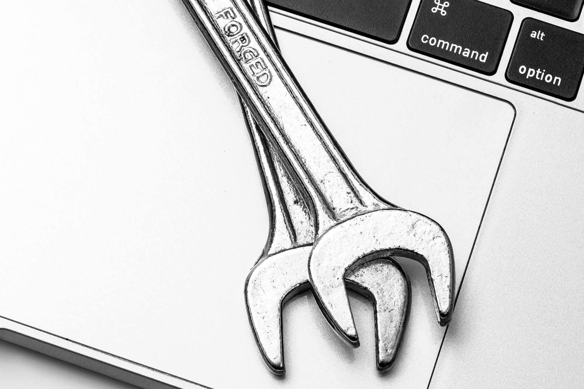 Two wrenches on top of a laptop keyboard.
