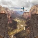 A man jumping over an impossibly large canyon with river below.