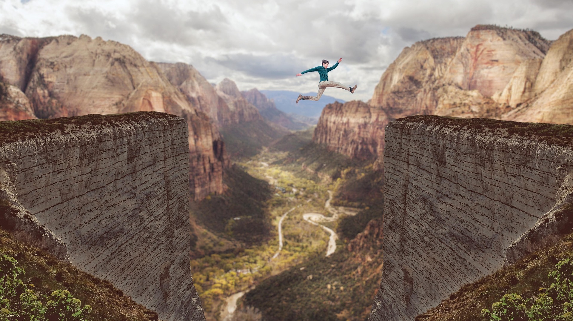 A man jumping over an impossibly large canyon with river below.