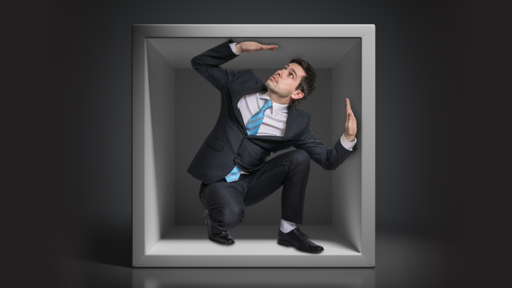 Businessman trapped in a small box, walls closing in.