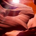 A photo of a canyon, winding through the rocks, sunlight up top shining down).