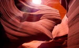 A photo of a canyon, winding through the rocks, sunlight up top shining down).