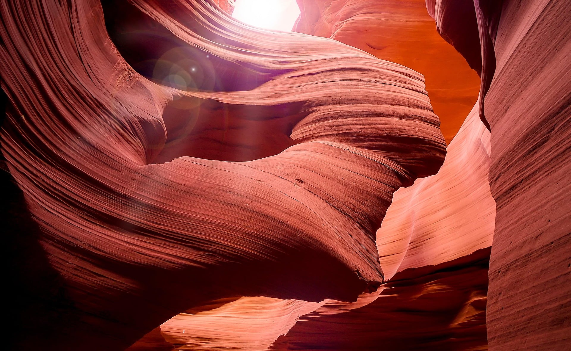 A photo of a canyon, winding through the rocks, sunlight up top shining down).