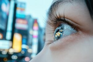 City lights reflecting in a woman’s wide open eye.
