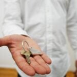 A person in background holding out a key in outstretched hand.