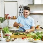 Male chef cooking in the kitchen, surrounded by a lot of kitchen tools and ingredients.