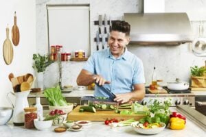 Male chef cooking in the kitchen, surrounded by a lot of kitchen tools and ingredients.