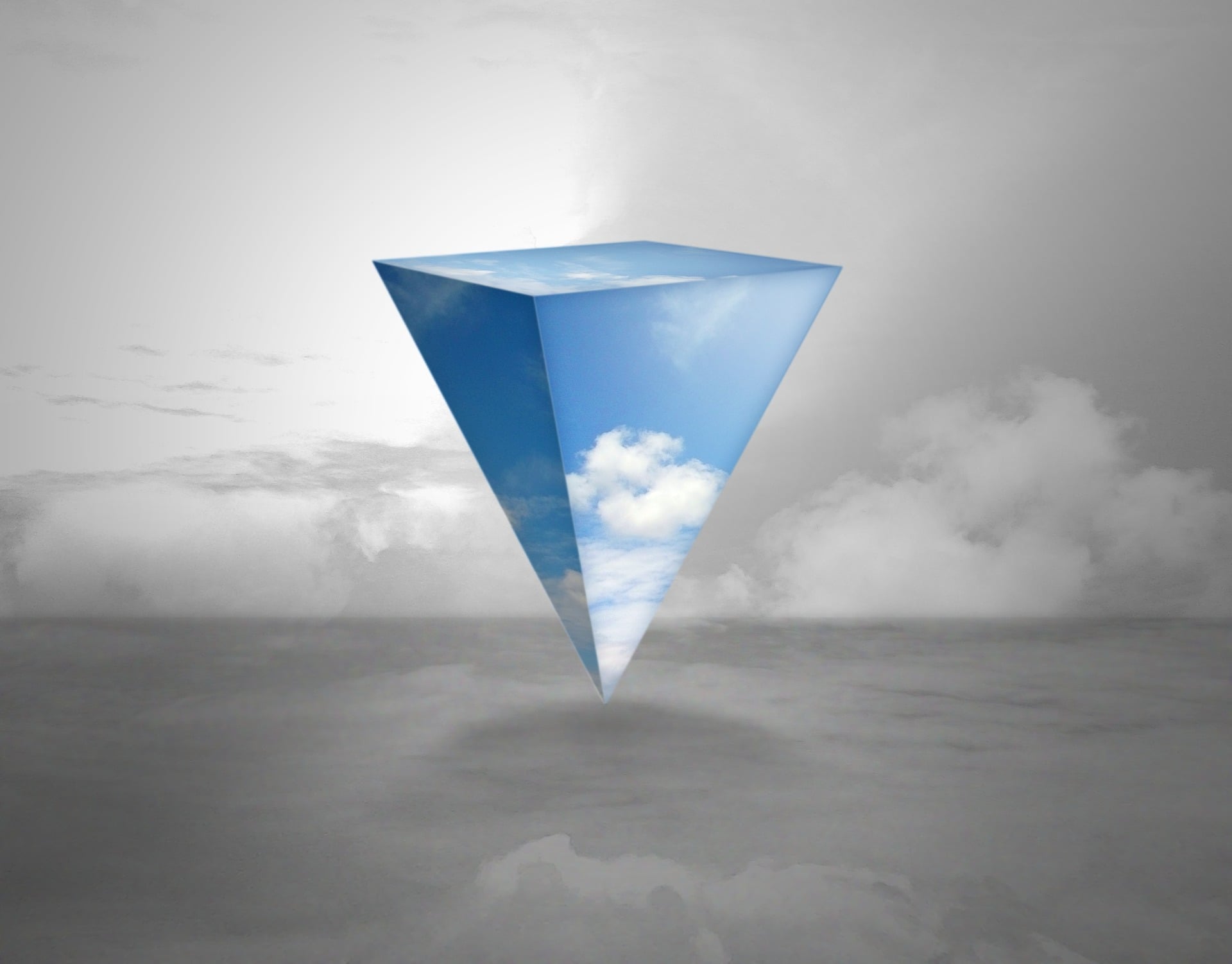 Surreal triangular prism with blue sky and clouds above gray horizon.